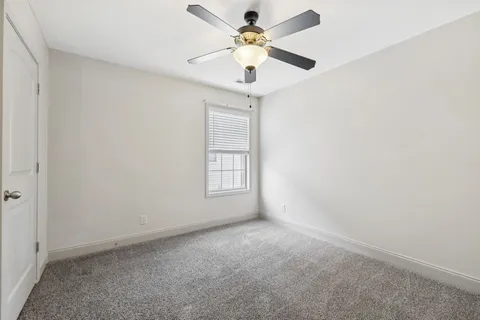 an empty room with a chandelier fan and windows