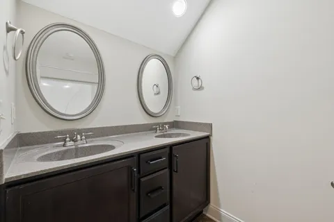 a bathroom with a granite countertop double vanity sink and a mirror