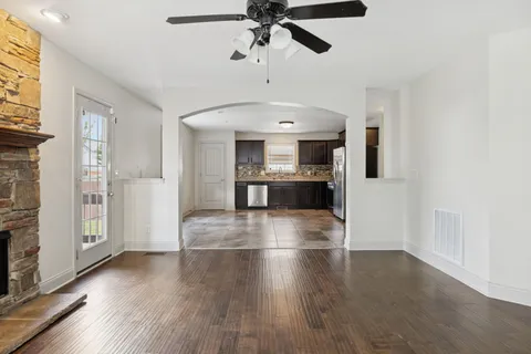 a view of a livingroom with wooden floor a ceiling fan and windows
