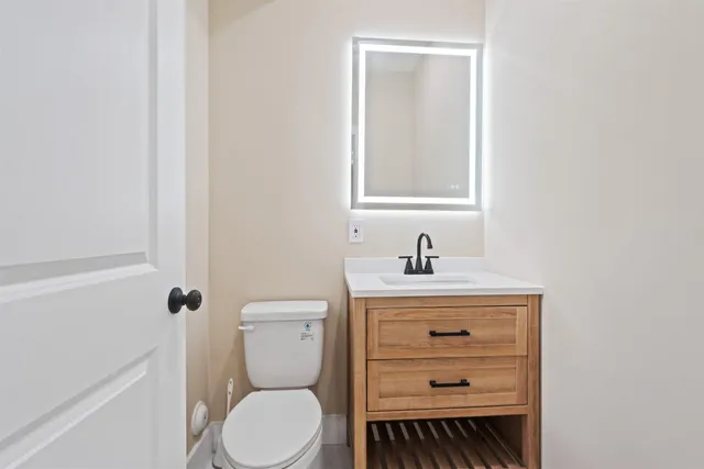 a bathroom with a toilet a sink a vanity and mirror