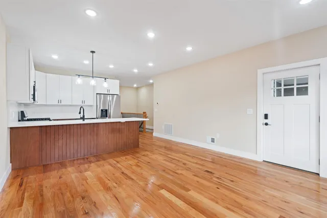a view of kitchen with kitchen island a sink wooden floor and a refrigerator