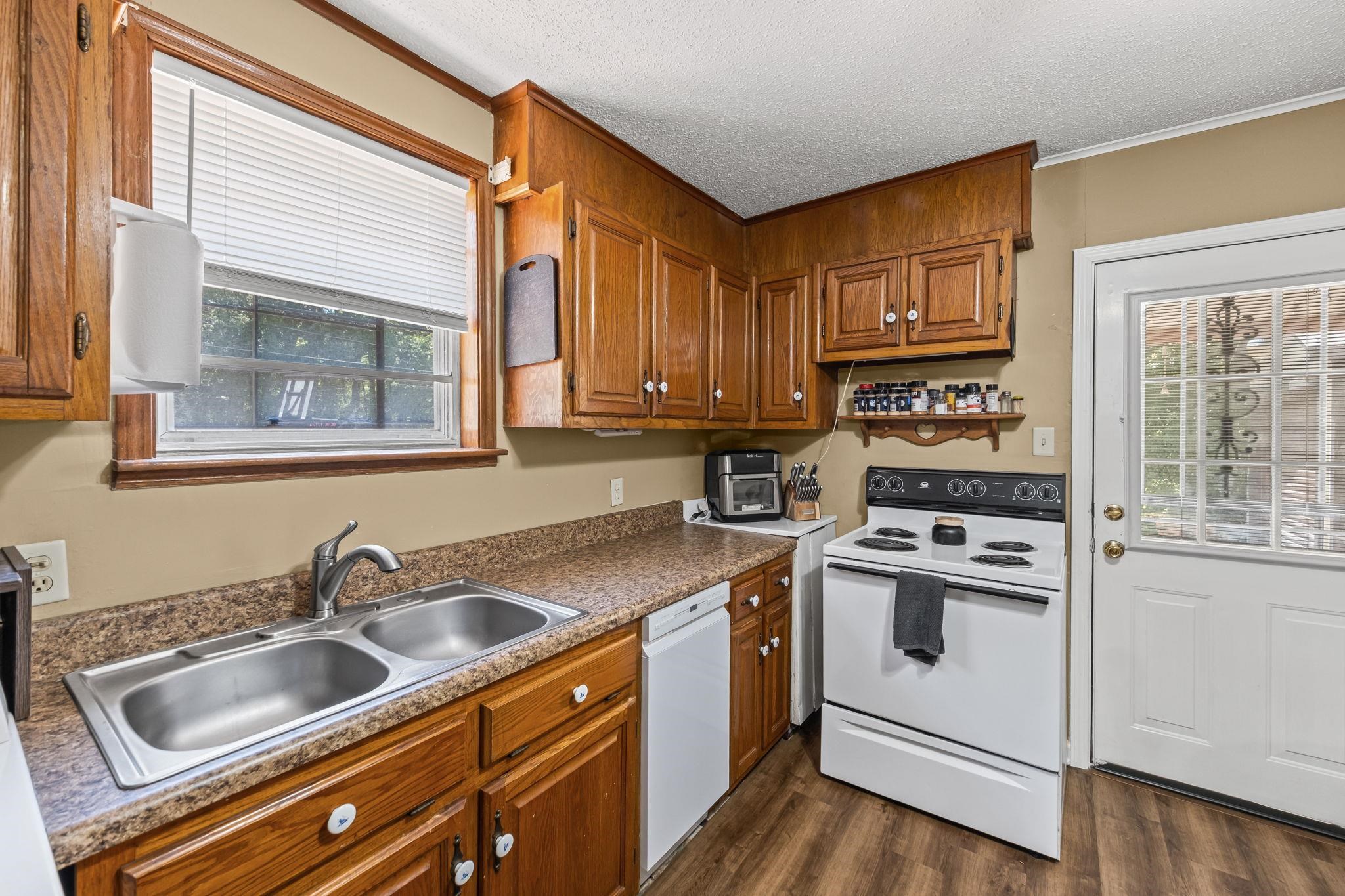 4140 Pleasant Ridge Road Millington, TN 38053 - Photo 11 of 30 Kitchen featuring brown cabinetry, white appliances, dark wood-style floors, a textured ceiling, and dark countertops