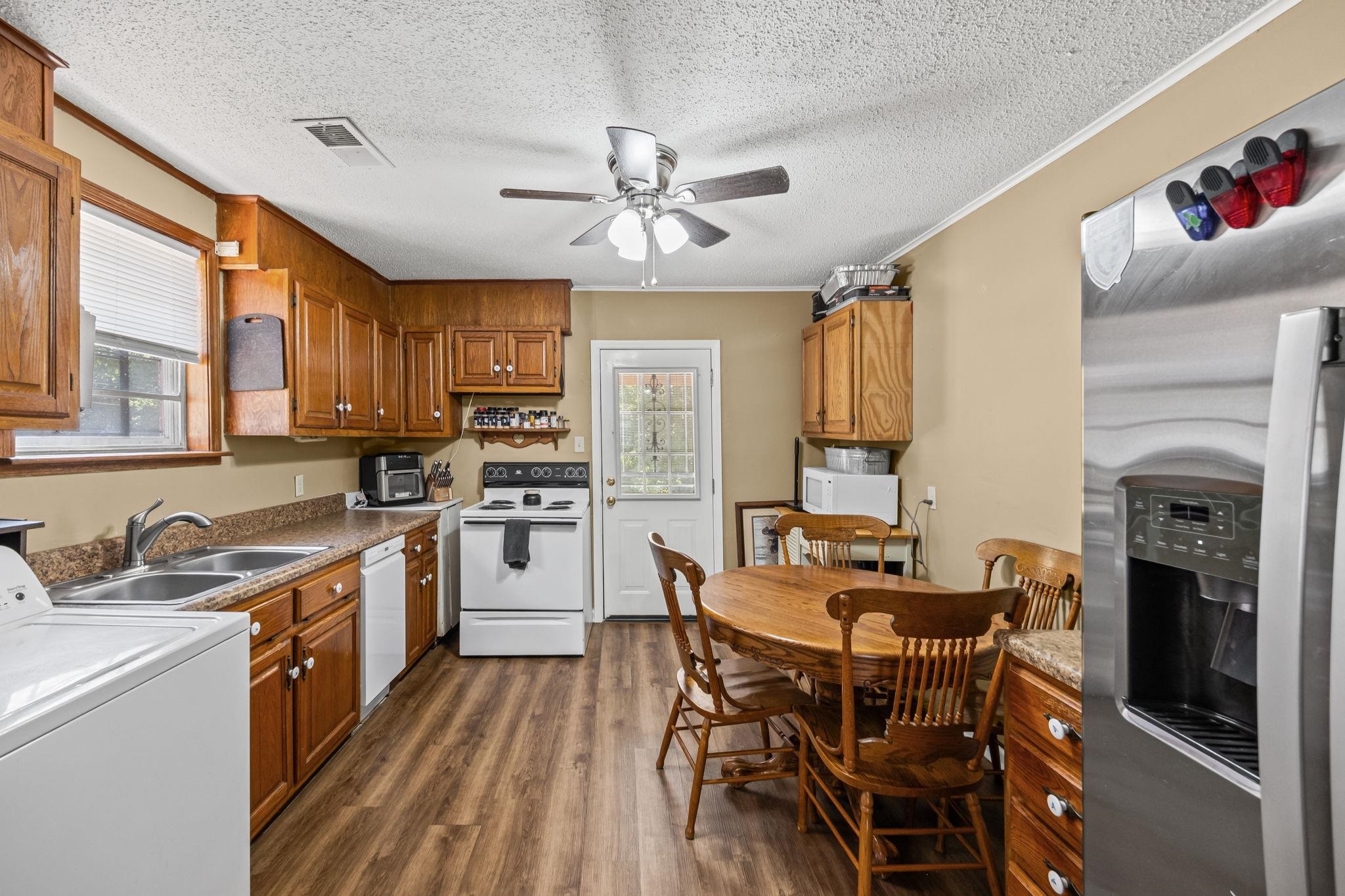 4140 Pleasant Ridge Road Millington, TN 38053 - Photo 12 of 30 Kitchen featuring washer / dryer, white appliances, brown cabinets, a textured ceiling, and dark wood-style flooring