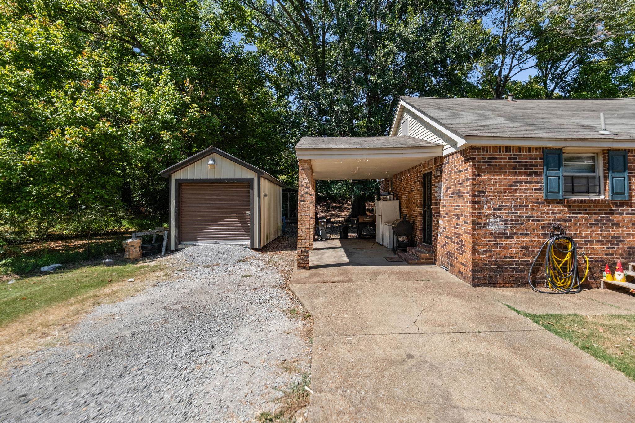 4140 Pleasant Ridge Road Millington, TN 38053 - Photo 28 of 30 View of side of home with gravel driveway, brick siding, an outbuilding, roof with shingles, and an attached carport
