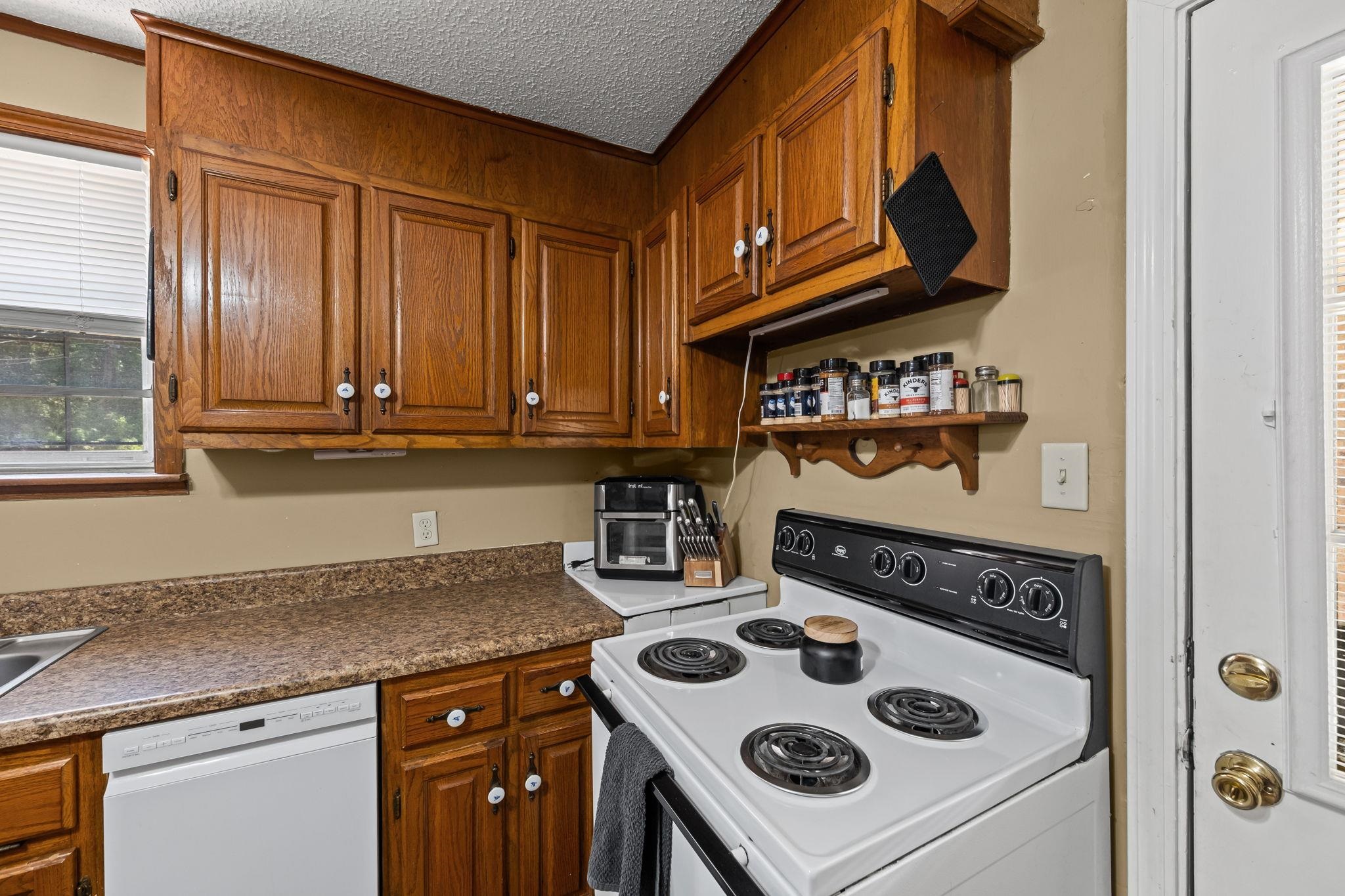 4140 Pleasant Ridge Road Millington, TN 38053 - Photo 9 of 30 Kitchen featuring white appliances, brown cabinets, a textured ceiling, dark countertops, and open shelves