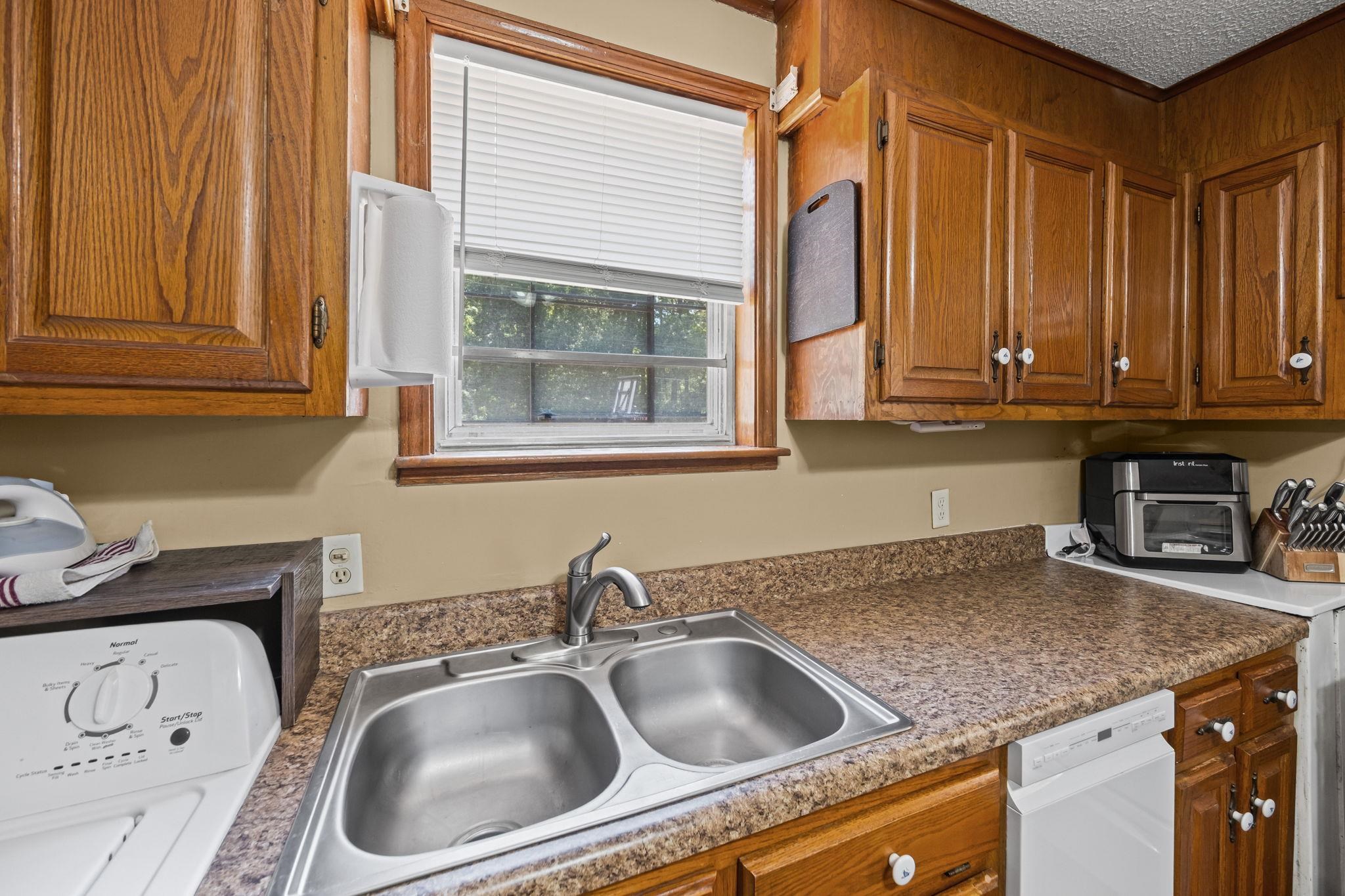 4140 Pleasant Ridge Road Millington, TN 38053 - Photo 10 of 30 Kitchen featuring brown cabinets, washer / dryer, white dishwasher, and dark countertops