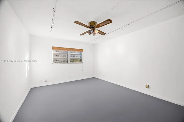 an empty room with a ceiling fan and window