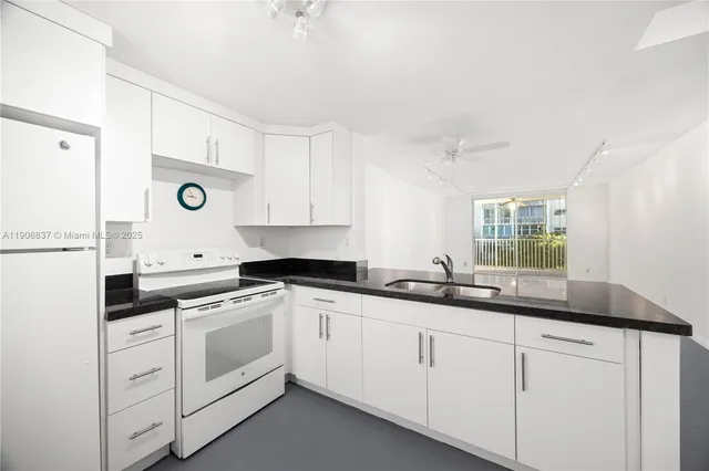 a kitchen with granite countertop white cabinets and white appliances