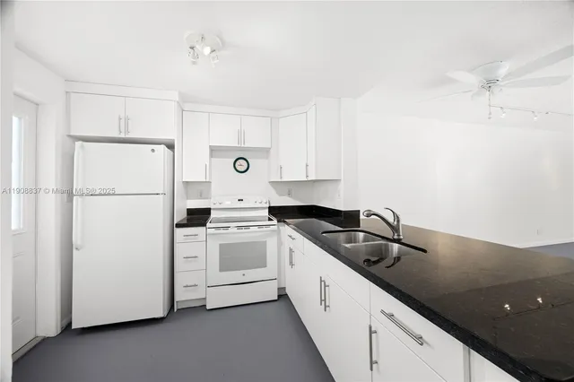 a kitchen with a sink a refrigerator and white cabinets