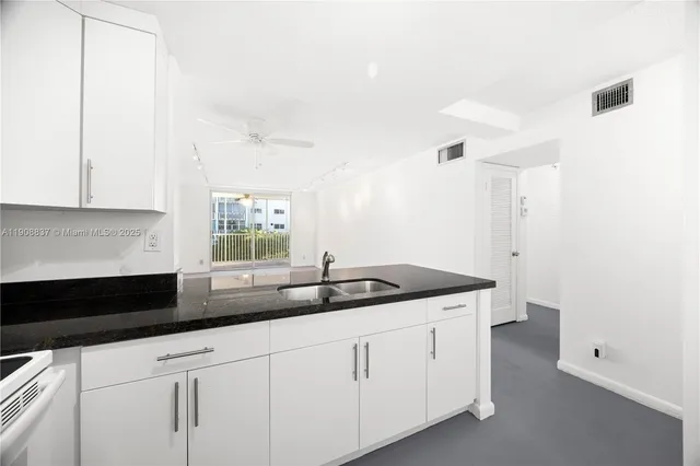 a kitchen with granite countertop white cabinets and a sink