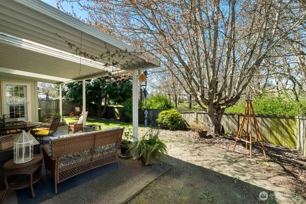 a view of a patio with table and chairs potted plants and large tree