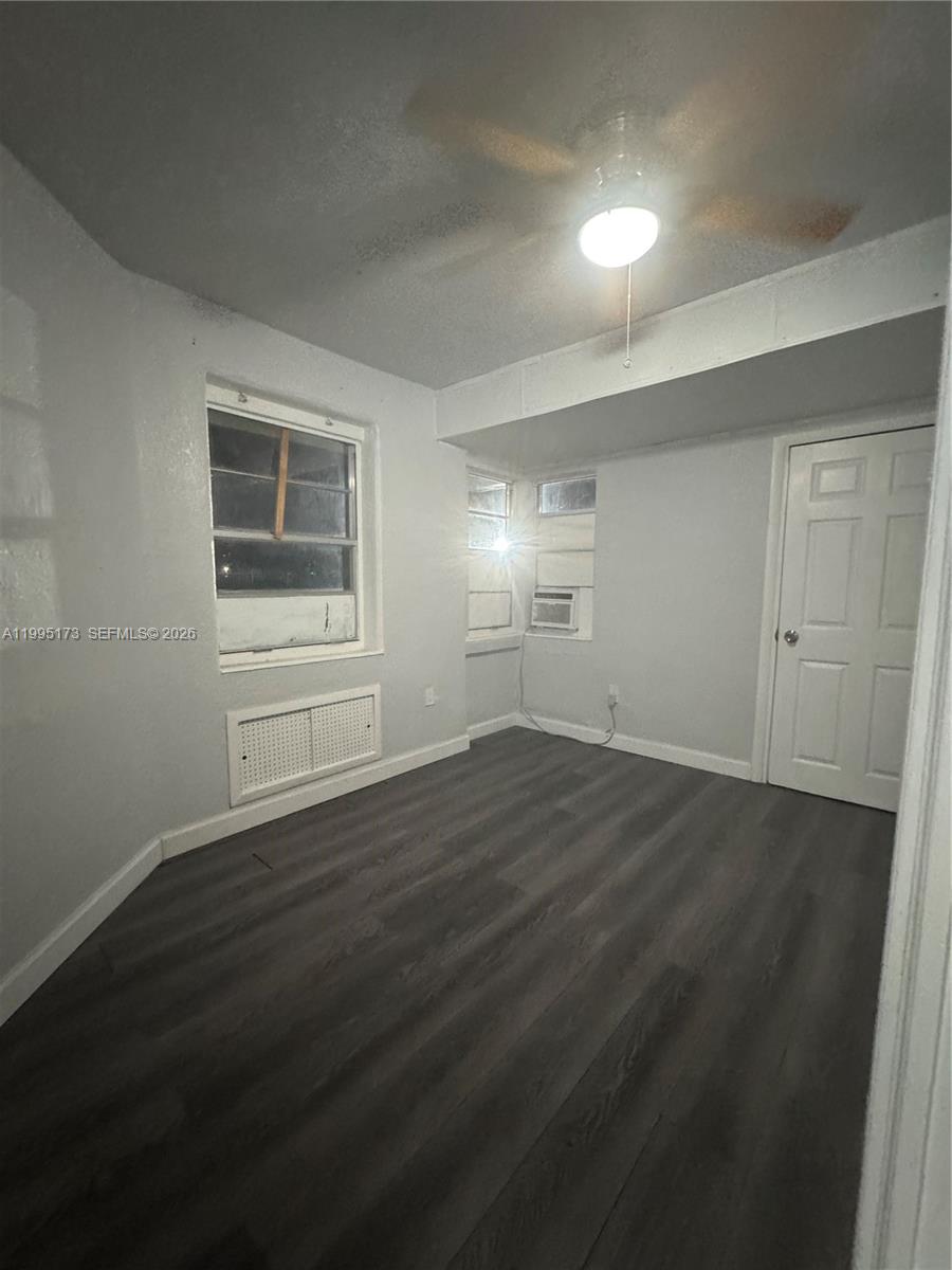 an empty room with wooden floor cabinet and windows