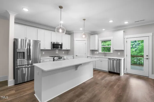 an empty room with wooden floor cabinet and windows
