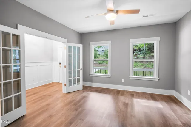 an empty room with windows and fan