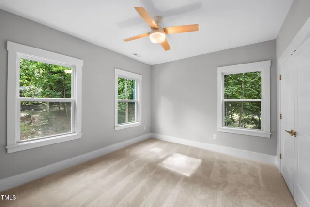 an empty room with windows and a ceiling fan