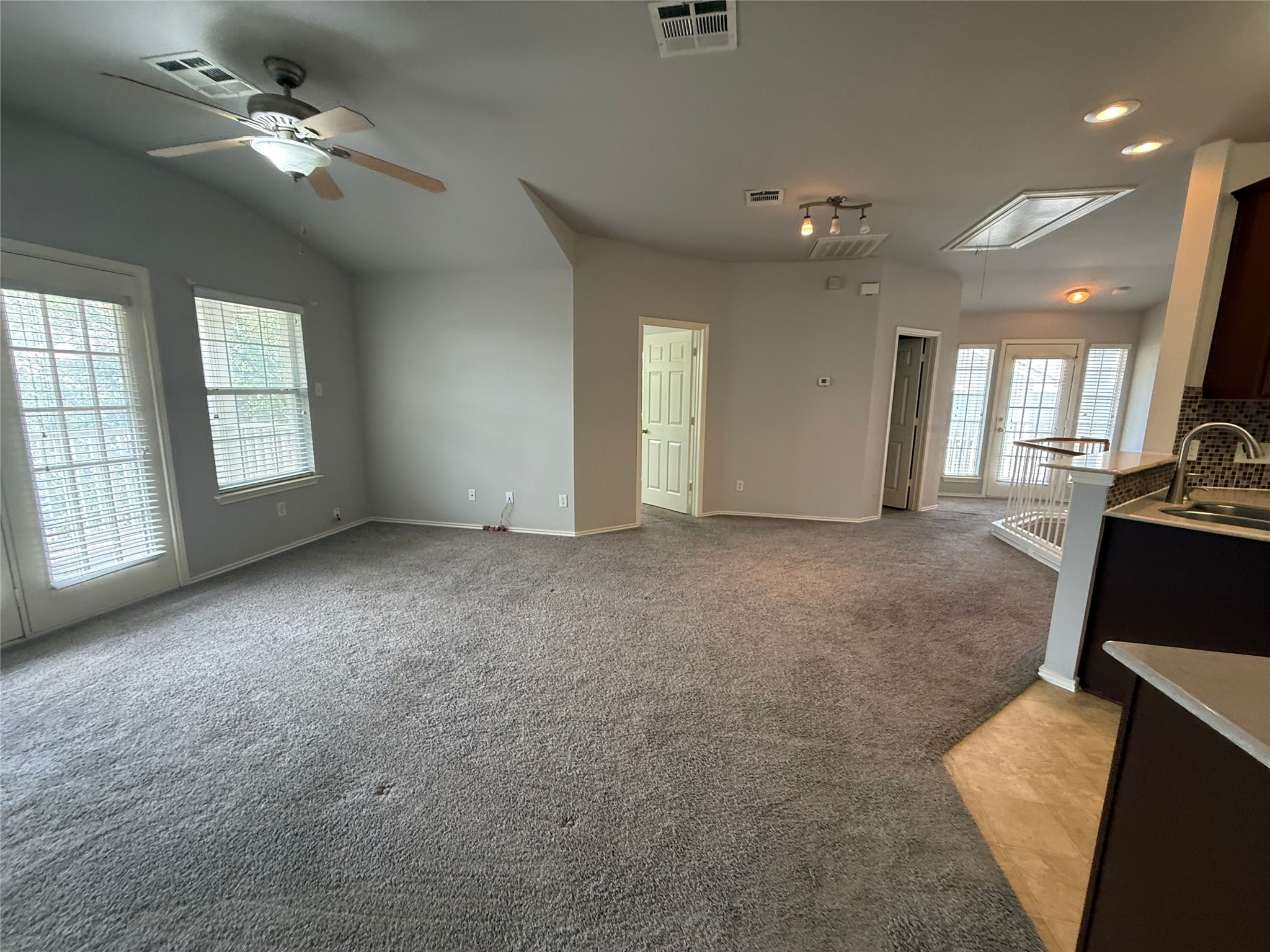 1900 Scofield Ridge Parkway, Unit 4701 Austin, TX 78727 - Photo 19 of 27 A spacious living area features high ceilings, soft carpet, and a seamless flow into the kitchen and dining spaces.