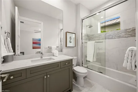 a bedroom with a large bed a chandelier and a flat tv screen on dresser