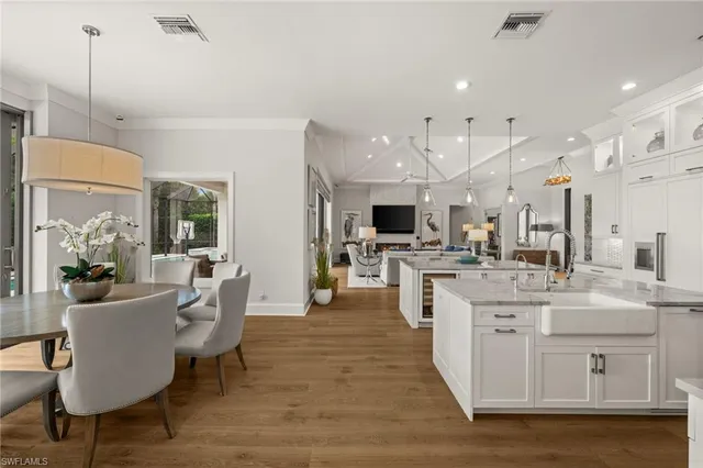 a large kitchen with cabinets chairs a sink and stainless steel appliances