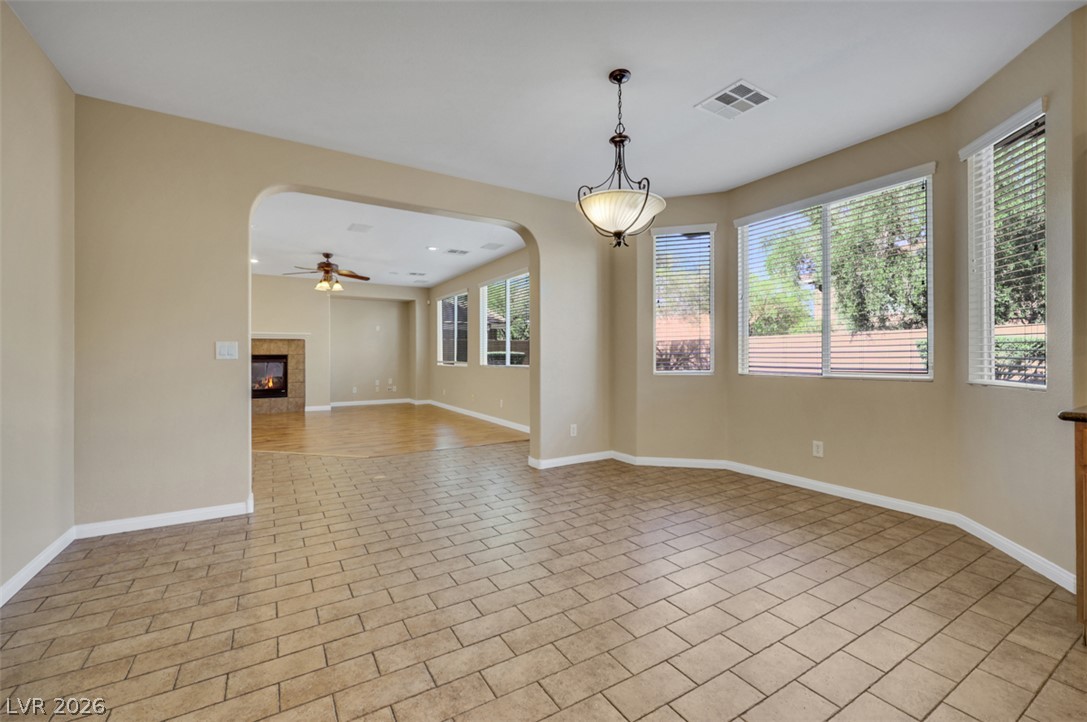 10328 Hawk Ravine Street Las Vegas, NV 89178 - Photo 12 of 55 Natural light floods this inviting living and dining area, featuring a cozy fireplace.