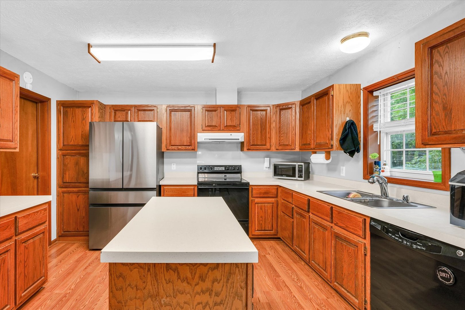 7795 Buttercup Road Weldon, IL 61882 - Photo 13 of 47 a kitchen with stainless steel appliances granite countertop a refrigerator a sink dishwasher a stove top oven and a dining table with wooden floor