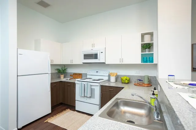 a kitchen with a refrigerator a stove a sink a microwave and cabinets