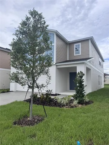 a view of a house with a yard and a large tree