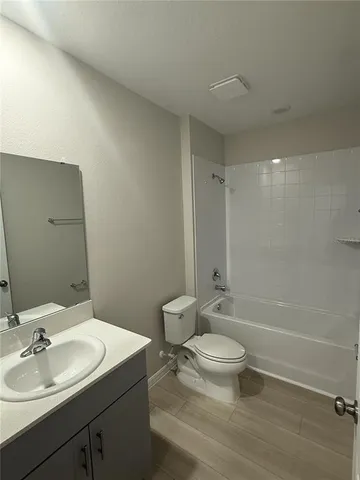 a bathroom with a granite countertop sink a toilet and shower