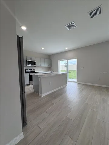 a kitchen with stainless steel appliances granite countertop a stove top oven a sink dishwasher and a refrigerator with wooden floor