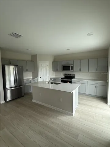a kitchen with granite countertop a refrigerator and a stove top oven