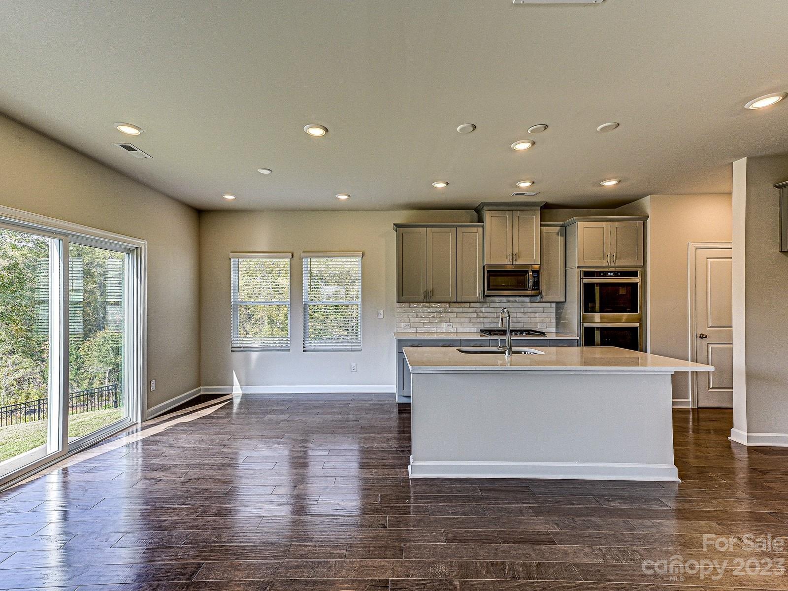 664 Citriadora Street Fort Mill, SC 29715 - Photo 4 of 27 a view of kitchen with stainless steel appliances granite countertop a stove top oven a sink and a large island with wooden floor