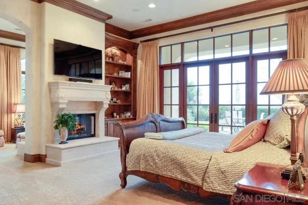 16537 Rd To Rio San Diego, CA 92127 - Photo 16 of 30 a bedroom with a bed a flat screen tv and a fireplace