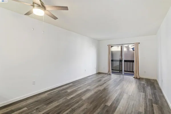 an empty room with wooden floor fan and windows