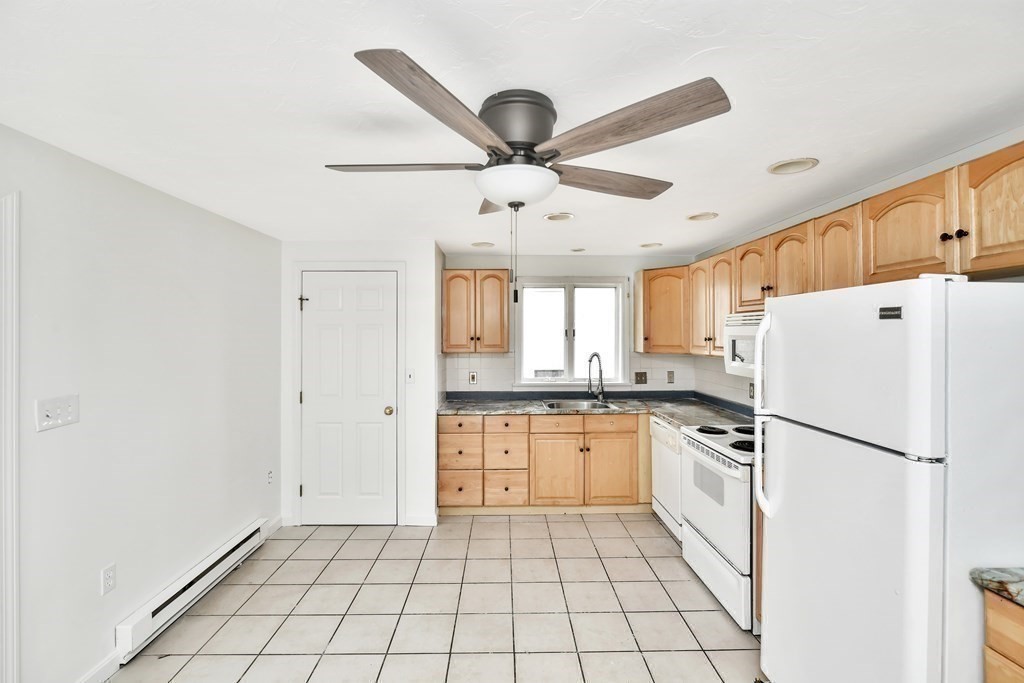 68 Marginal Street, Unit A Boston, MA 02128 - Photo 4 of 21 a kitchen with white cabinets a sink a stove and a refrigerator