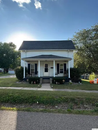 a front view of a house with garden and trees