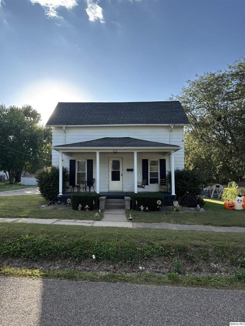 a front view of a house with garden and trees
