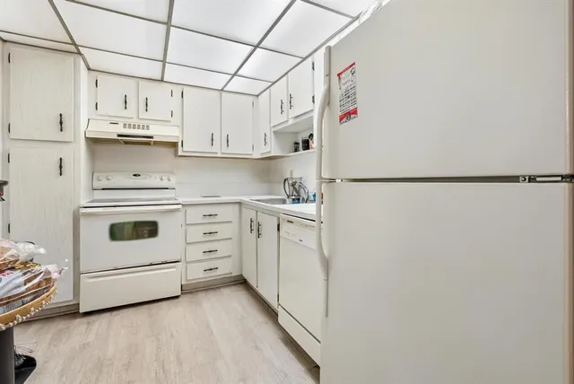 a view of a kitchen with white cabinets and white appliances