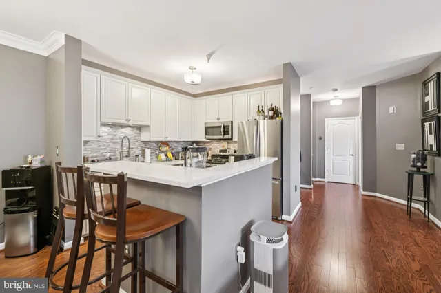 a kitchen with stainless steel appliances a dining table chairs refrigerator and cabinets