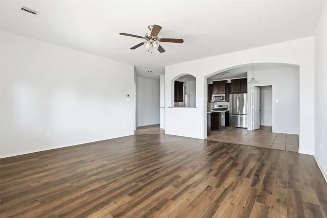 a view of empty room with wooden floor and ceiling fan