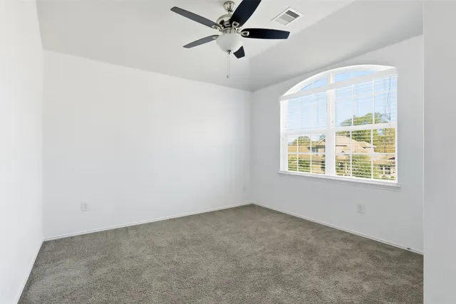 an empty room with a window and a ceiling fan