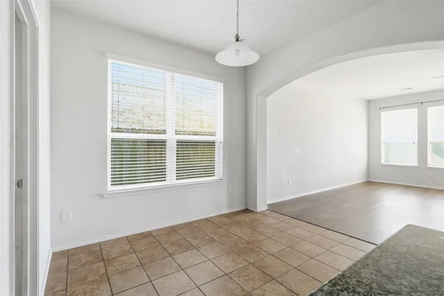 a view of an empty room with window and chandelier fan