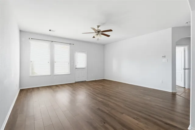 an empty room with wooden floor and windows