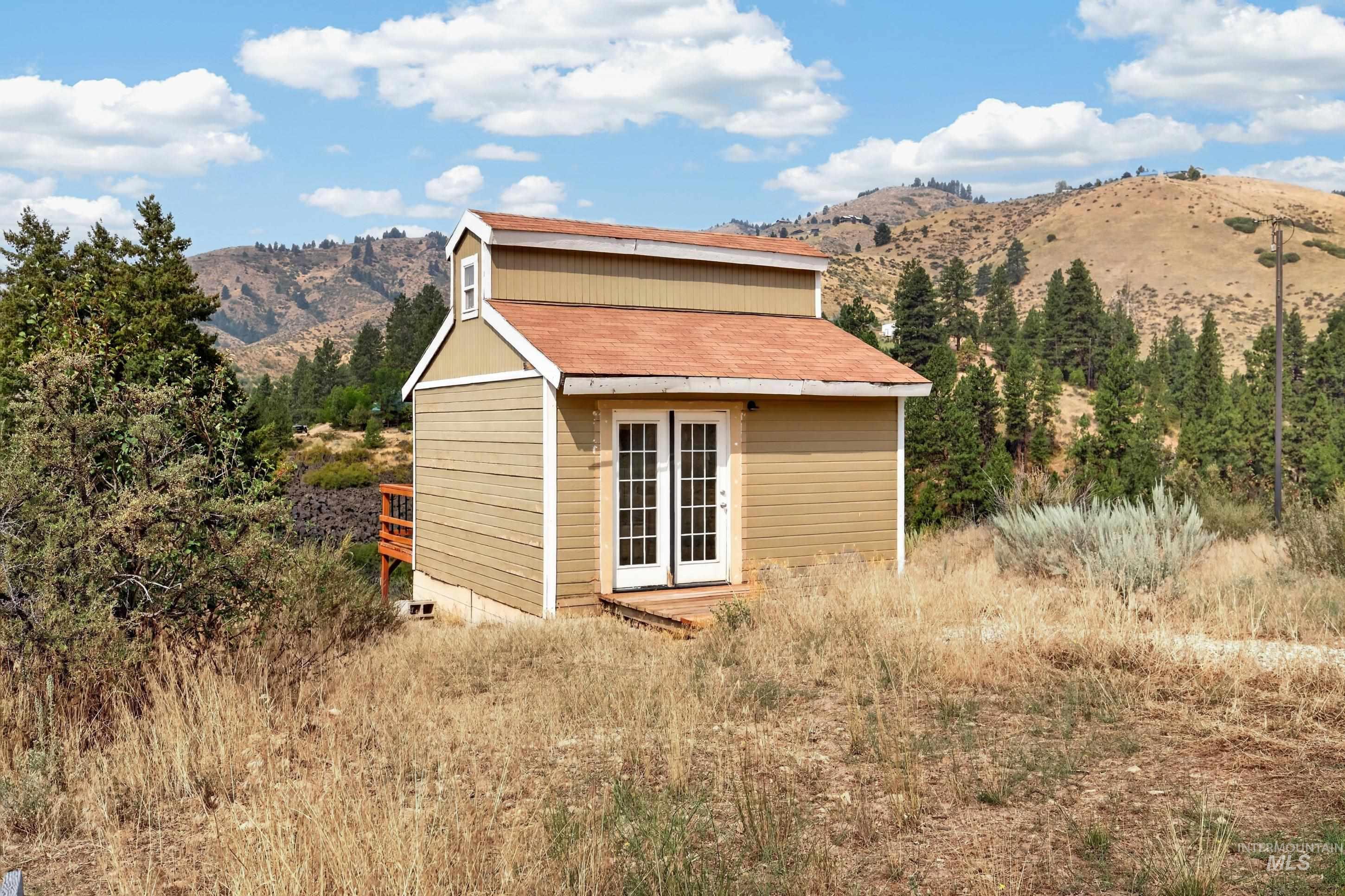 132 Mores Creek Rim Road Boise, ID 83716 - Photo 43 of 44 Compact structure with a dormer and two-panel French doors, set against a mountainous backdrop