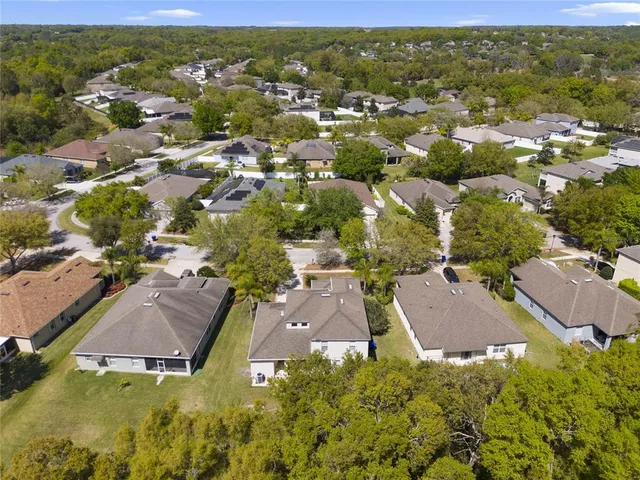 an aerial view of residential houses with outdoor space and trees
