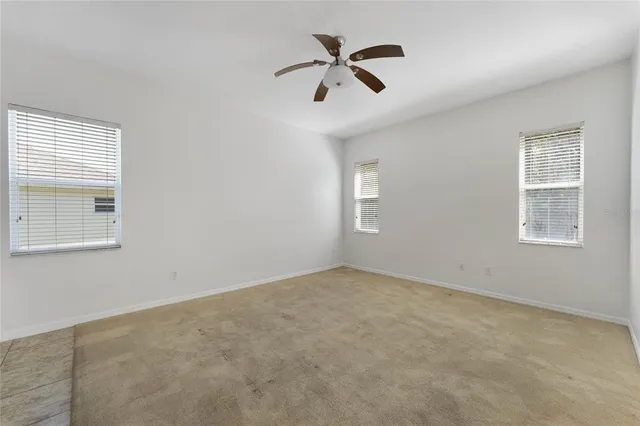 an empty room with windows and fan