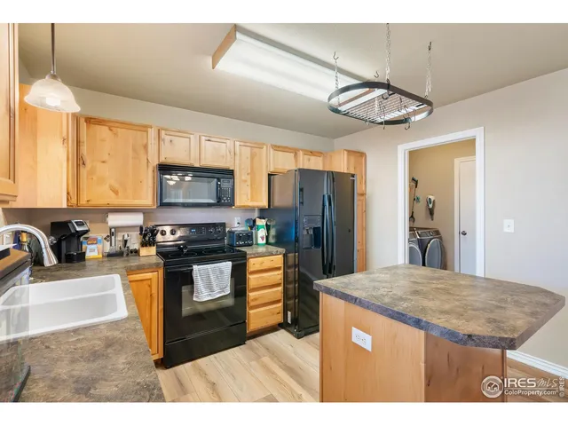 a kitchen with stainless steel appliances granite countertop a sink a stove a refrigerator cabinets and chairs