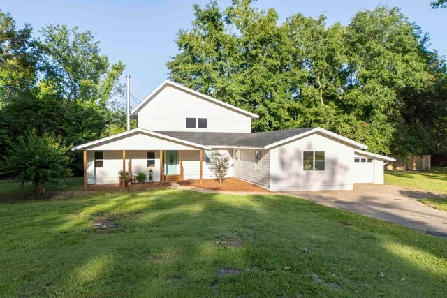 a front view of a house with a yard and trees