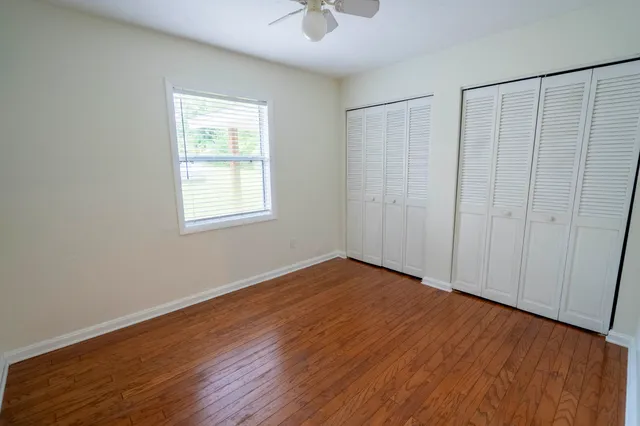 an empty room with wooden floor cabinet and windows