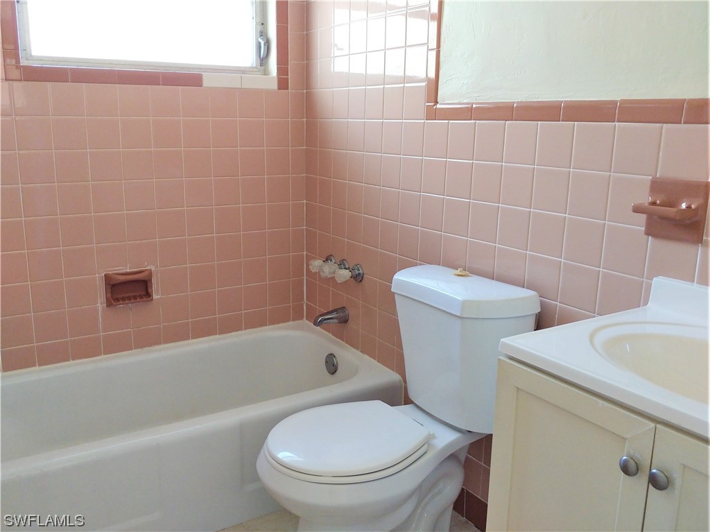 112 Clayton Avenue Lehigh Acres, FL 33936 - Photo 10 of 16 a white toilet and tub sitting next to a bathroom sink