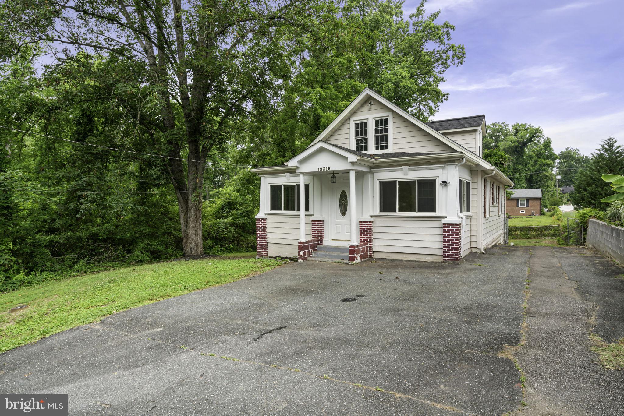 a white house that has a small yard and large trees