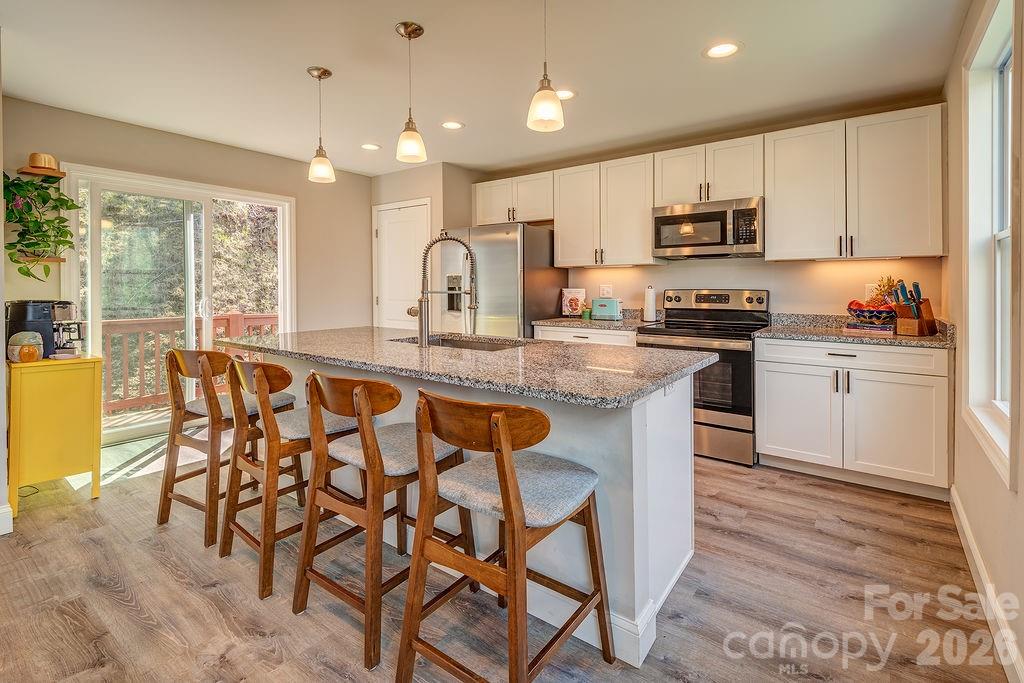 343 Garren Creek Road Fairview, NC 28730 - Photo 12 of 30 a kitchen with stainless steel appliances granite countertop a stove top oven a sink dishwasher and white cabinets with wooden floor